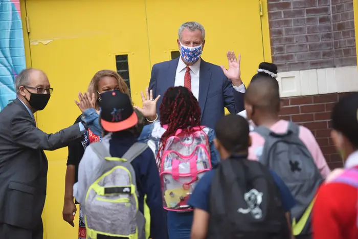 Mayor de Blasio and Schools Chancellor Porter give high fives to kids in a school yard